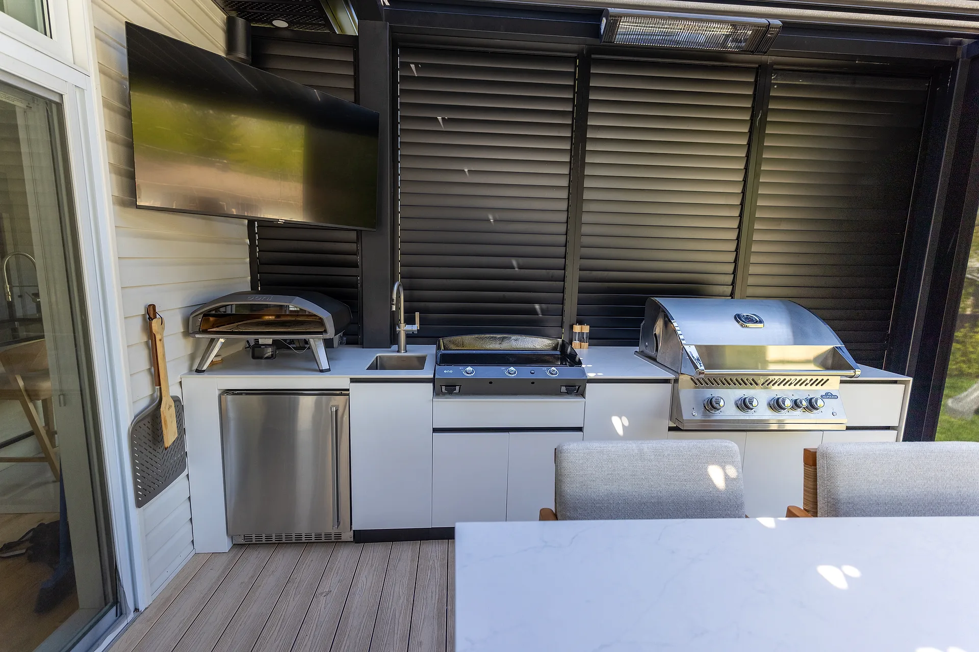 Détail de la cuisine extérieure à Mascouche — four à pizza, plancha Eno, BBQ Napoléon, évier et frigo de marque maison avec comptoirs Orastone