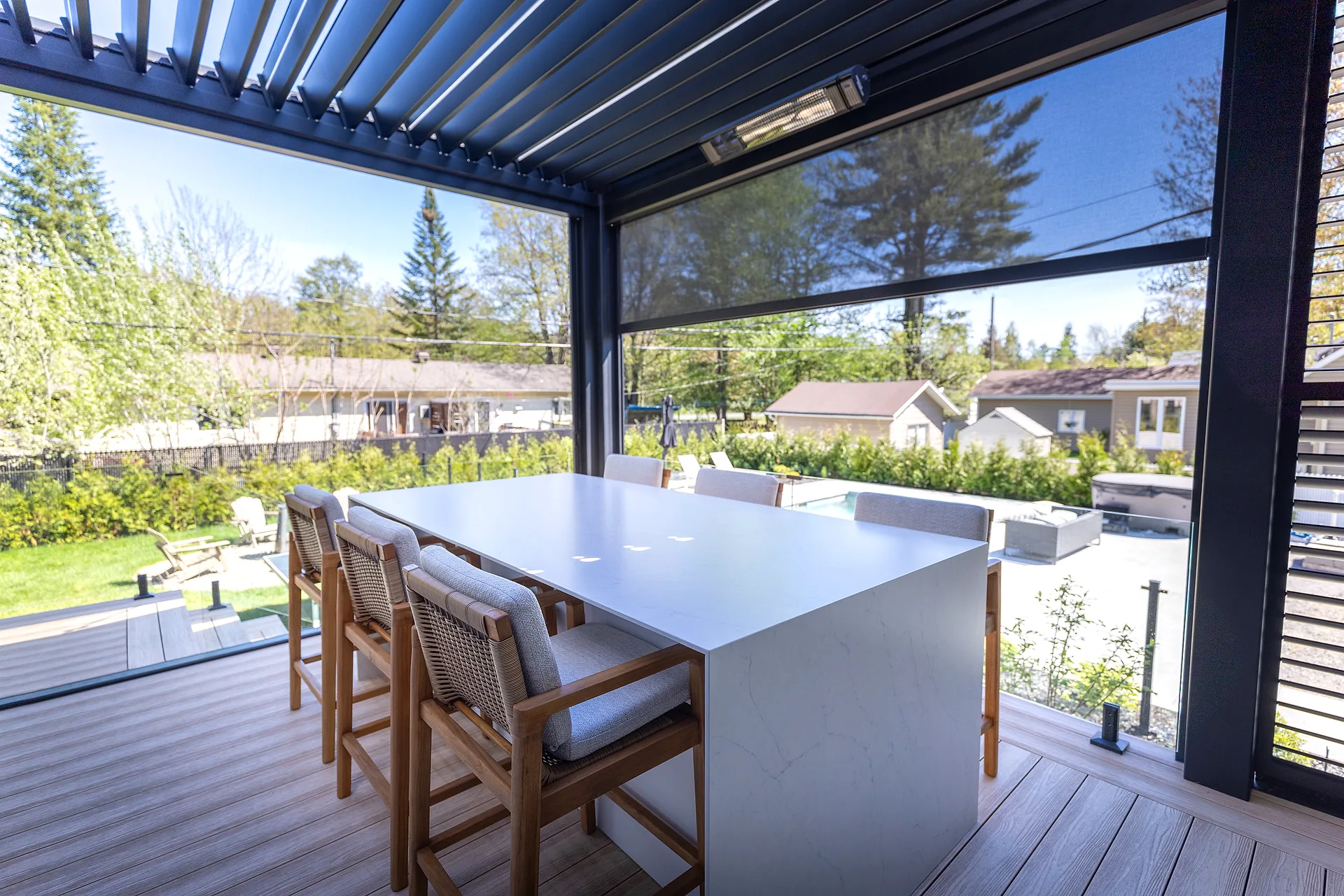 A planned, turnkey outdoor kitchen: hosting table under a pergola, overlooking the landscaped yard