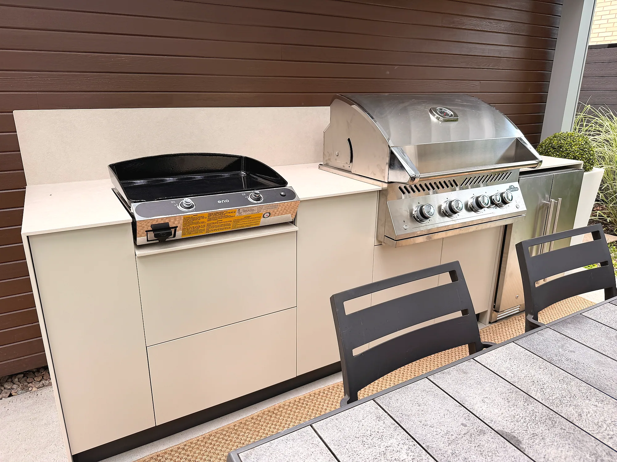 Ligne de cuisson en gros plan avec plancha à deux brûleurs et BBQ Napoléon série 700 sous comptoir Orastone Oat, projet Grenon