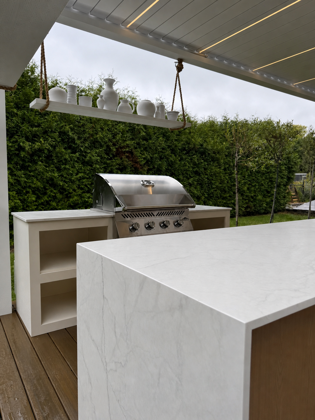Outdoor kitchen under a pergola with an Orastone sintered-stone counter, built-in BBQ, and custom fronts.